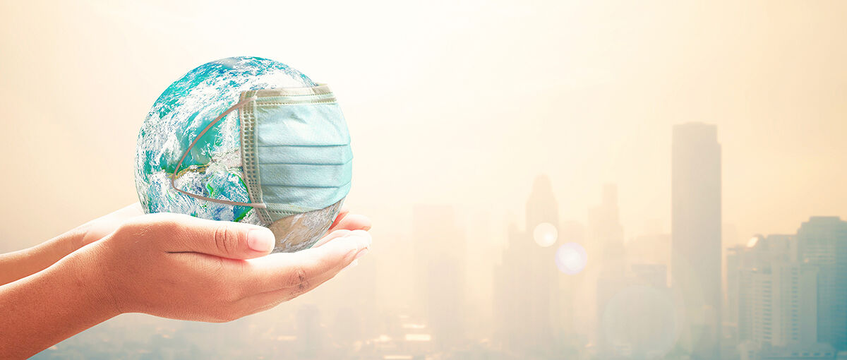 Human hands holding earth globe with medical disposable face mask. Elements of this image furnished by NASA