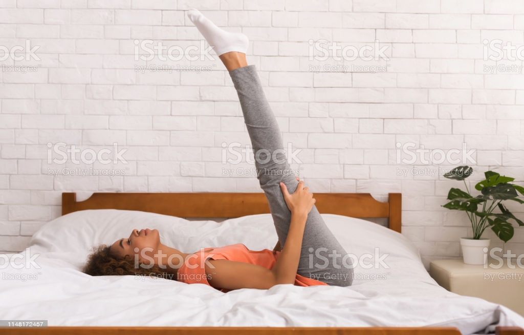 Morning workout in bedroom. Woman doing yoga exercise on bed at home