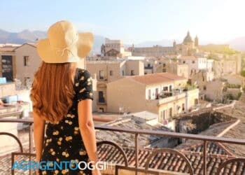 Young lady looking Palermo cityscape from balcony at sunset in Italy
