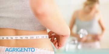 Closeup of a young woman measuring her waist in the bathroom