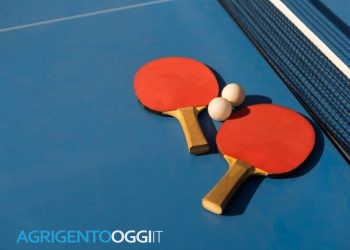 Table tennis ping pong paddles and white ball on blue board