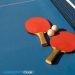 Table tennis ping pong paddles and white ball on blue board