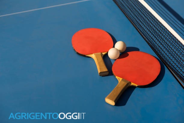 Table tennis ping pong paddles and white ball on blue board